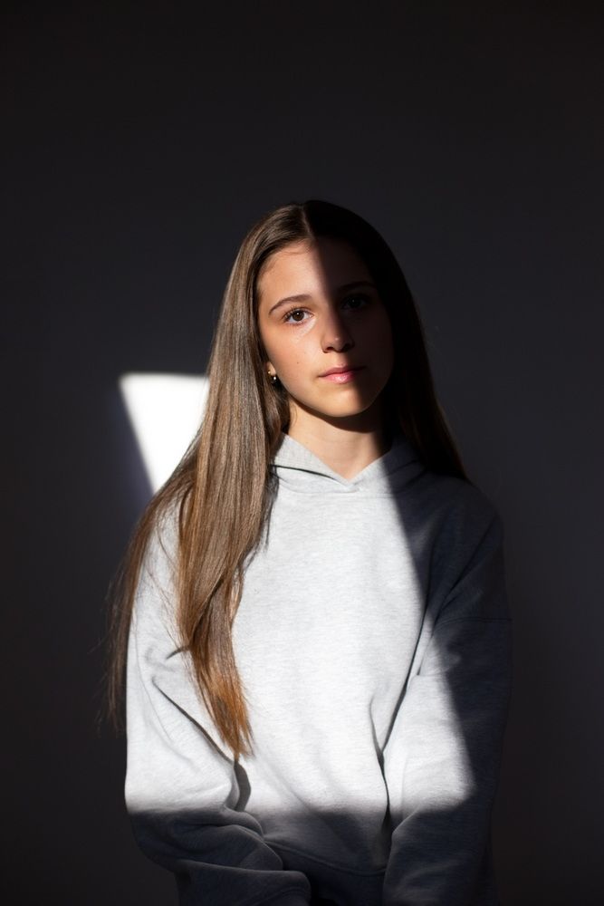 Portrait eines Mädchens, was halb direkt angeleuchtet wird und halb im Schatten ist und den Kopf so neigt