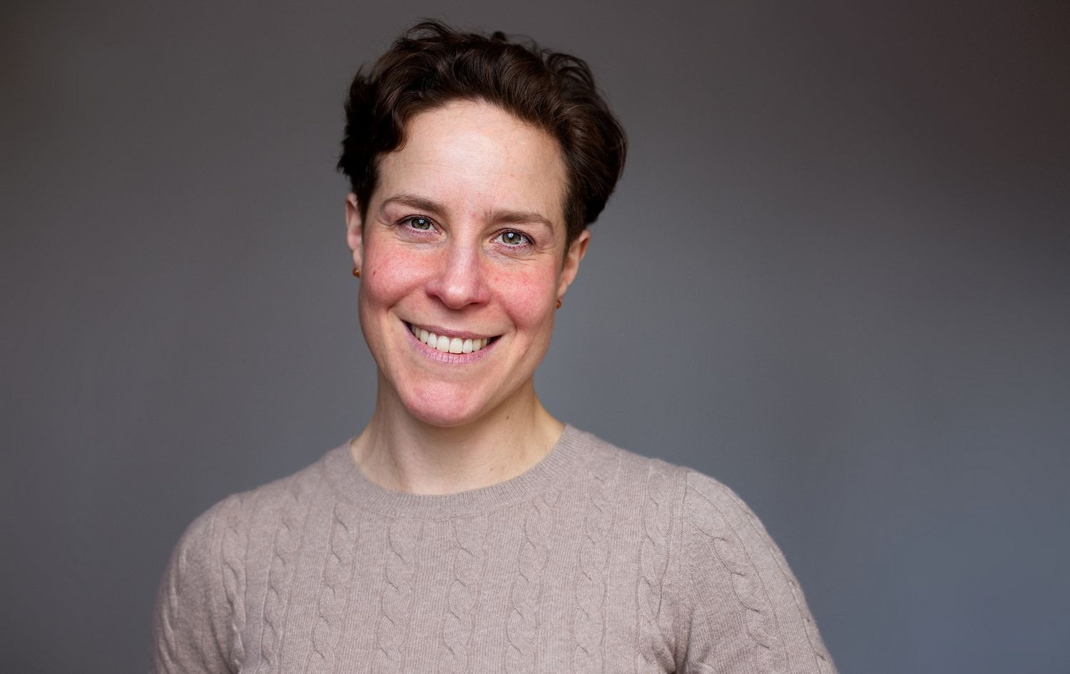 Portrait einer Frau mit einem beigem Pulli und dunklem Hintergrund