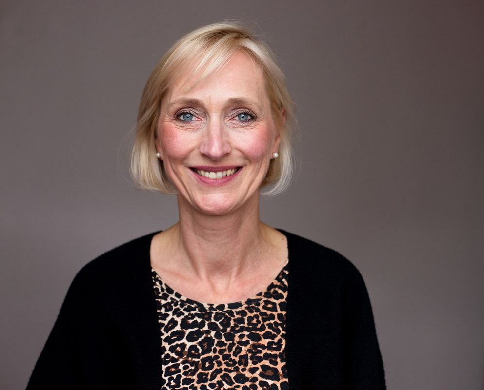 modernes Bewerbungsbild einer Frau mittleren Alters mit einer bluse mit Leoprint und einer schwarzen Strickjacke