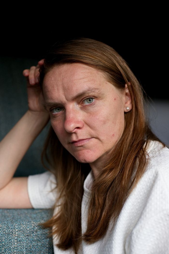 Selbstportrait der Fotografin mit weißem Oberteil, zurückgelehnt und einem ausdruckkstarken Blick