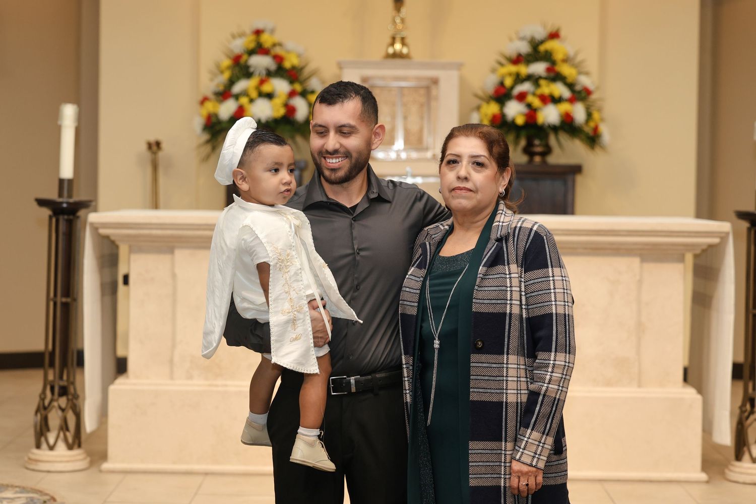 Family poses together in front of church altar with floral arrangements.
