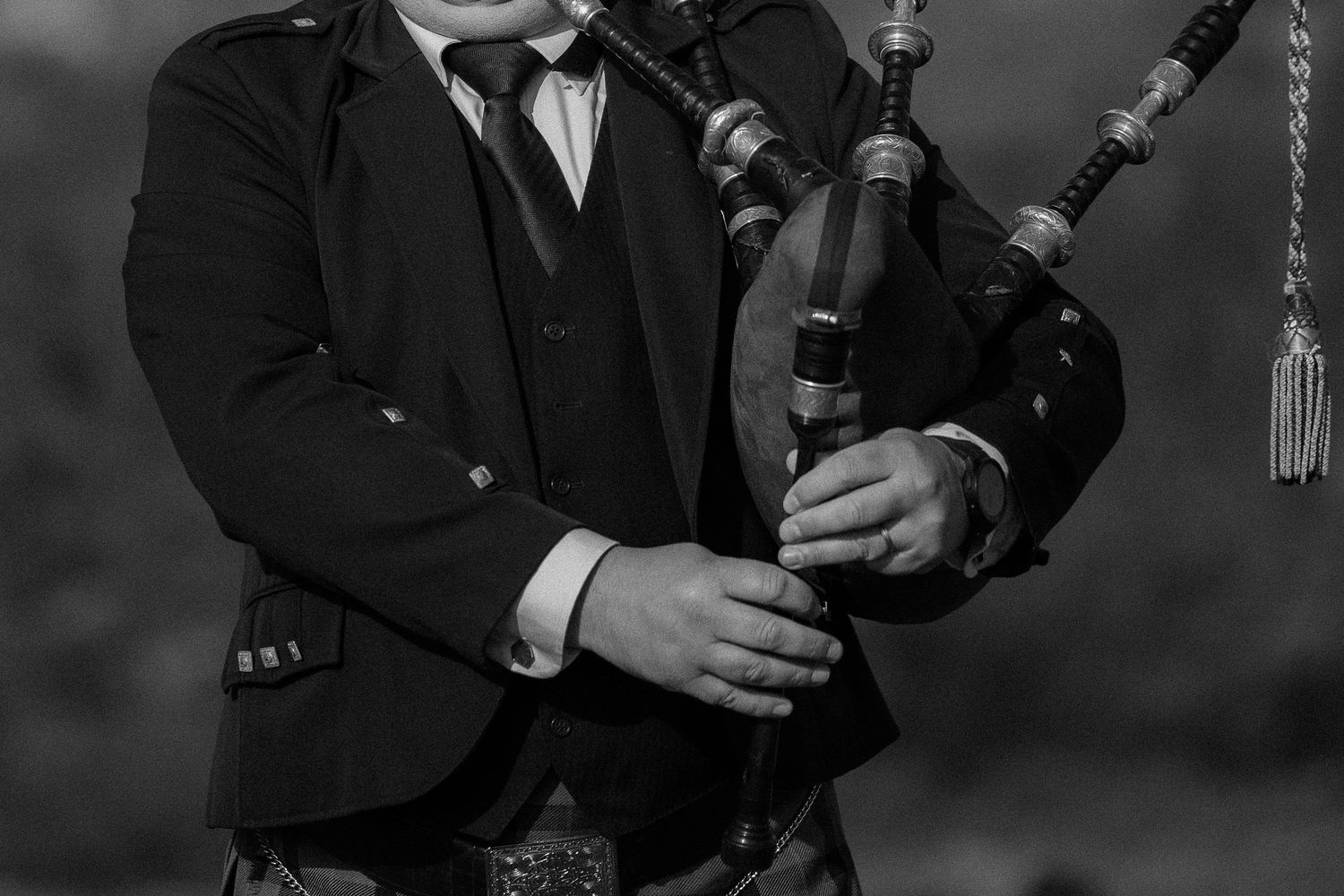 Musicians playing traditional bagpipes at formal event in black attire.