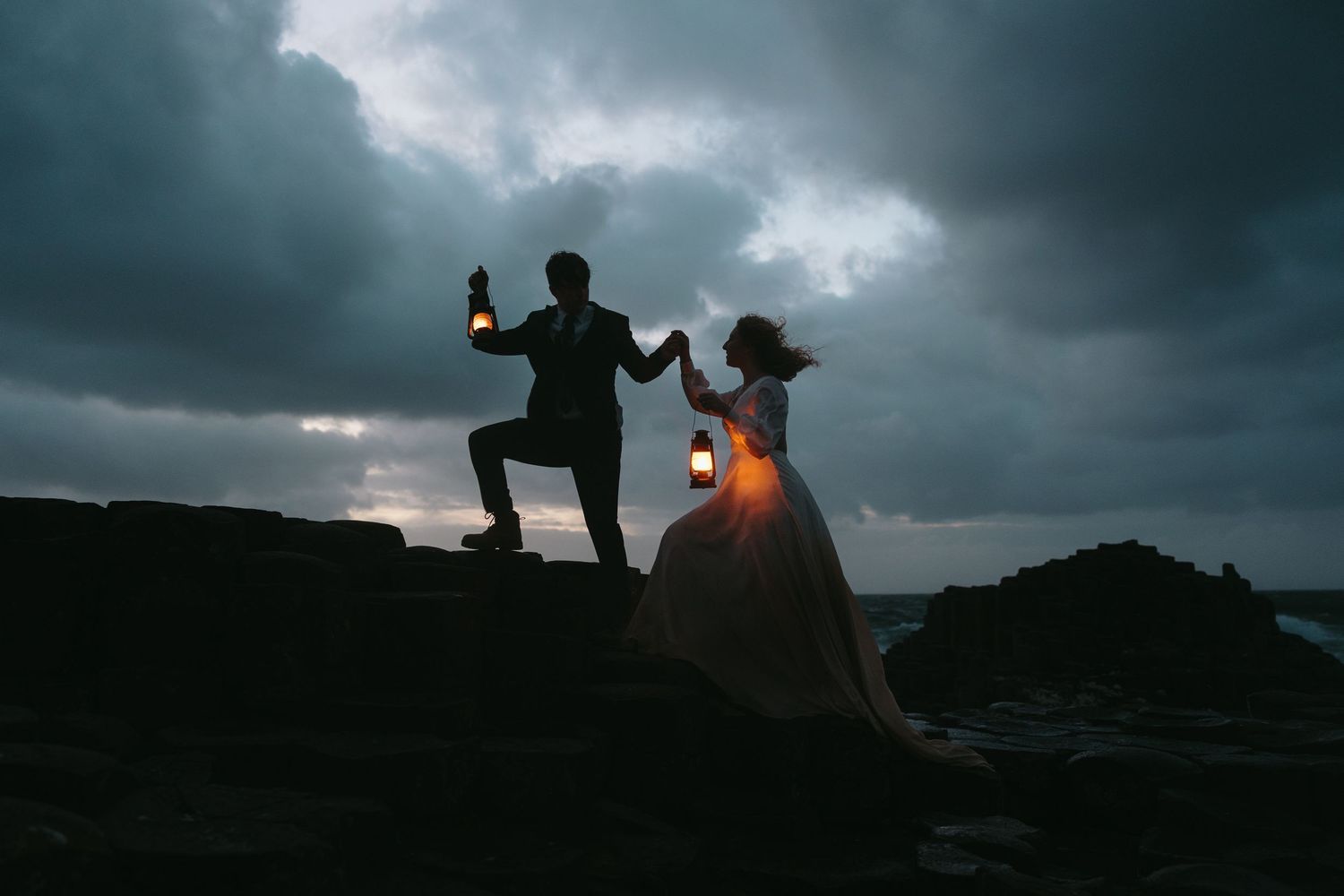 Silhouetted figures against stormy skies during sunset celebration.
