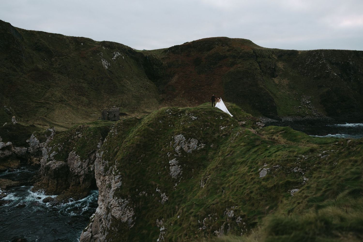 Dramatic aerial view of rugged coastal cliffs along the Irish coastline on a cloudy day.