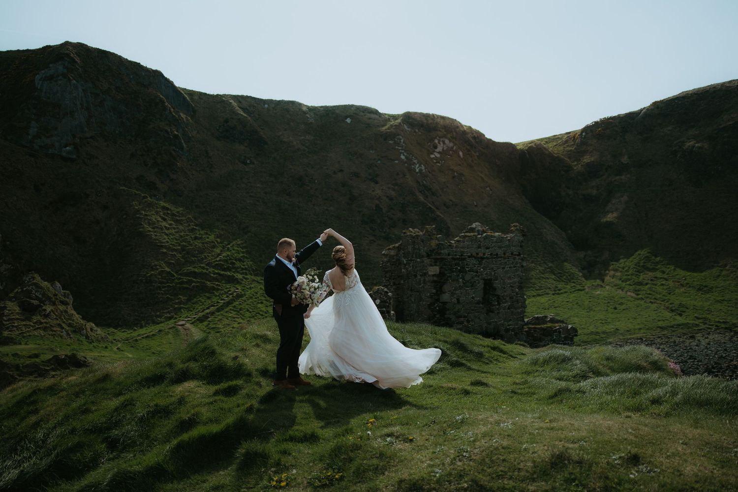 A wedding portrait captured against rolling green hills and mountains.