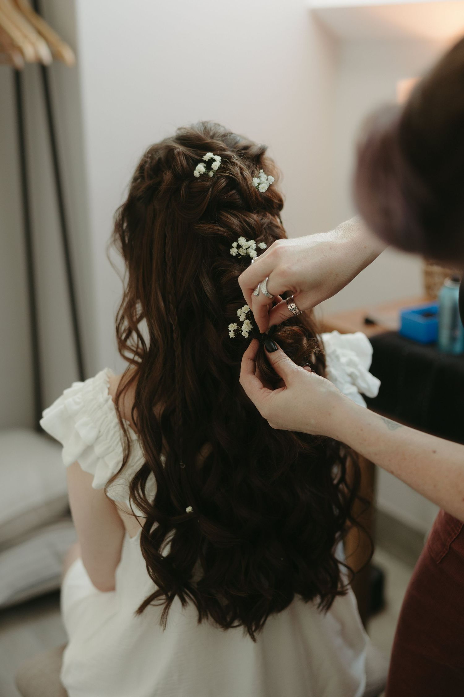 Wedding hair styling session showing hands placing delicate floral accessories.