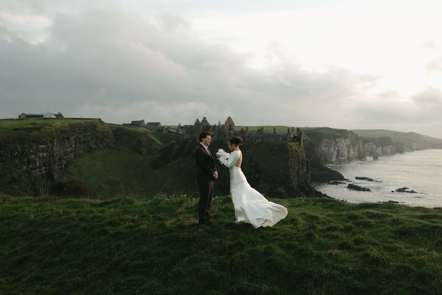 Wedding photography session on dramatic Irish coastal cliffs under cloudy skies.