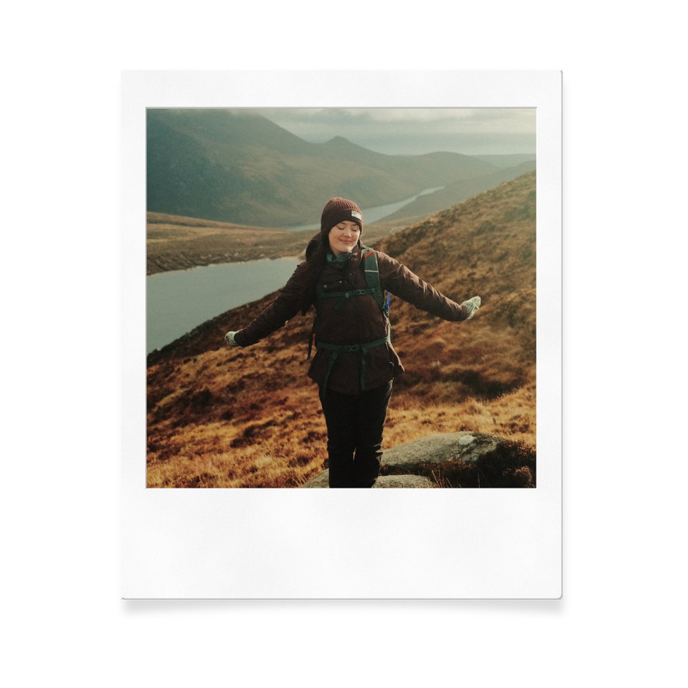 Polaroid capture of someone enjoying mountain views with arms spread wide.
