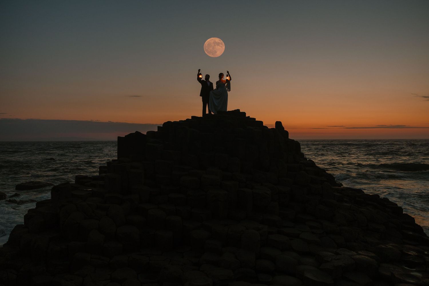 A romantic moment captured at the Giant's Causeway with crashing waves in the background.
