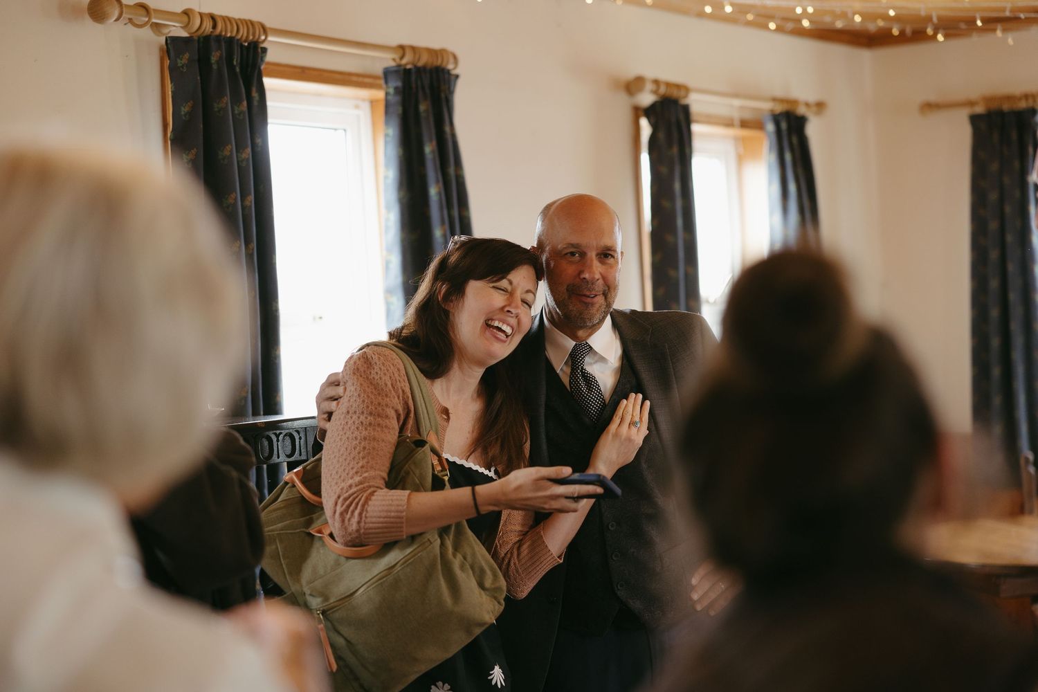 People dancing and celebrating at an indoor wedding reception with string lights and dark curtains in the background.