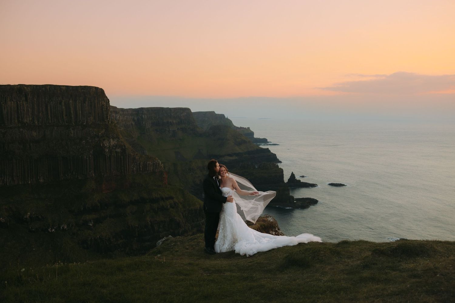 Dramatic sunset silhouettes figures against rugged coastal cliffs and ocean views.