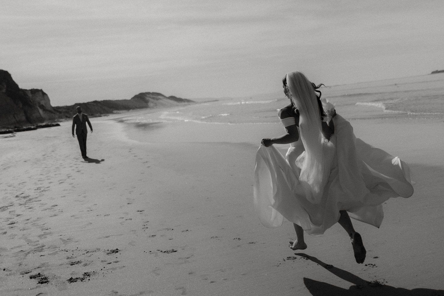 Bride running towards groom with dress flowing behind her on Whiterocks Beach, Portrush.