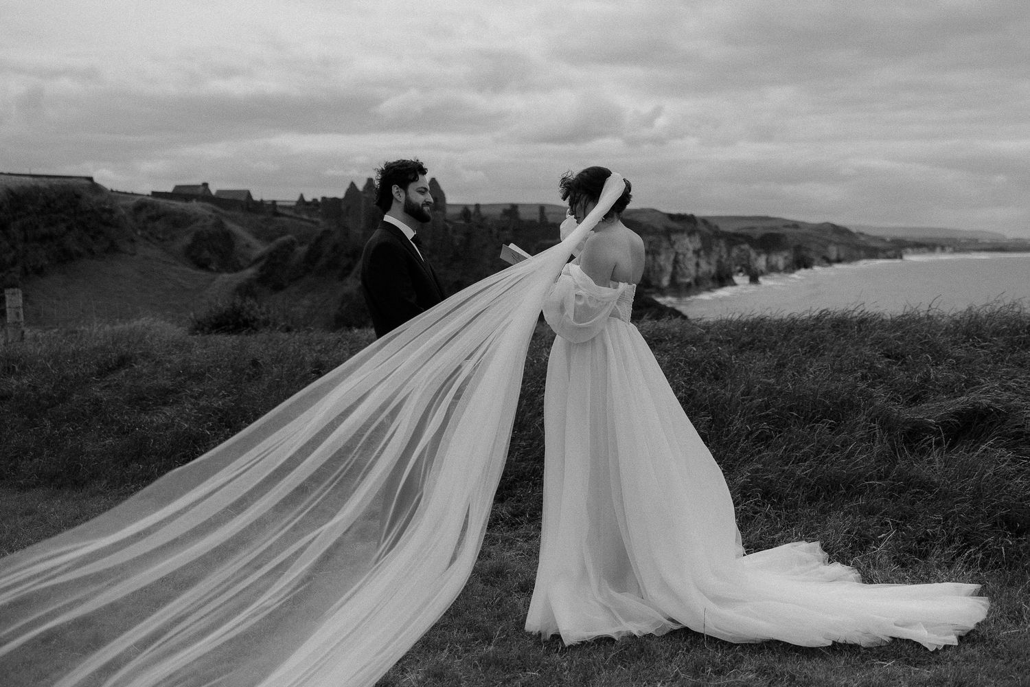 A scenic black and white wedding photo series showing a bride in a flowing dress against dramatic coastal landscapes.