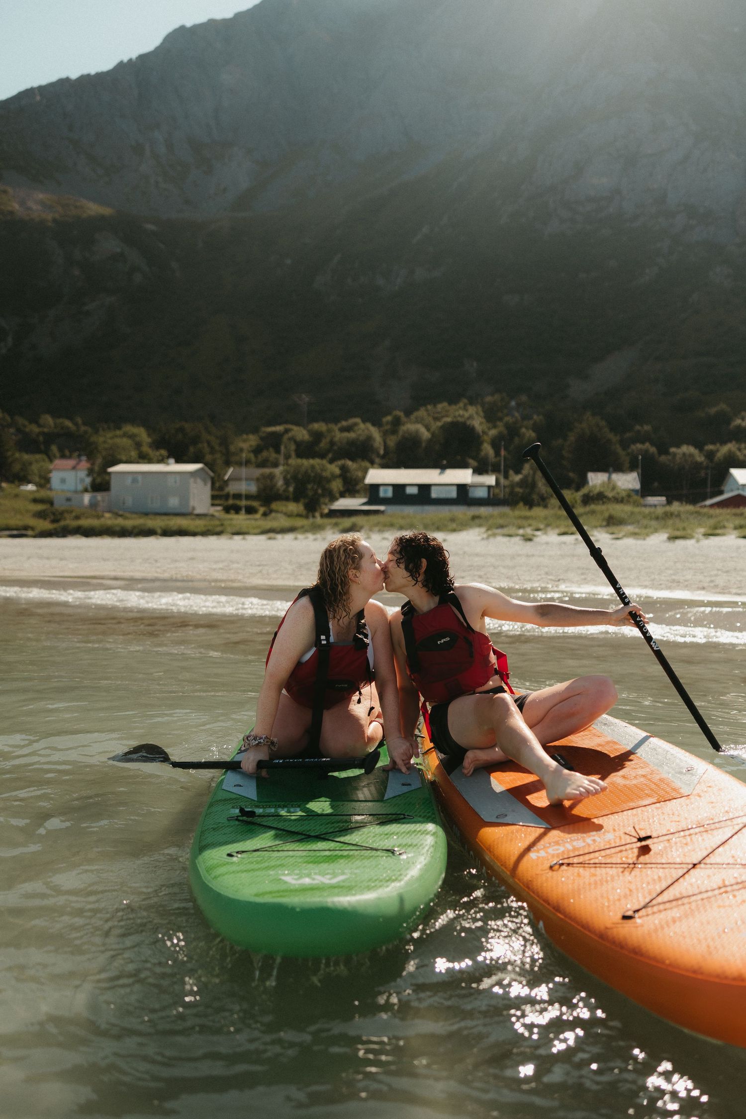 Colorful kayaks floating in calm waters with mountains in background.