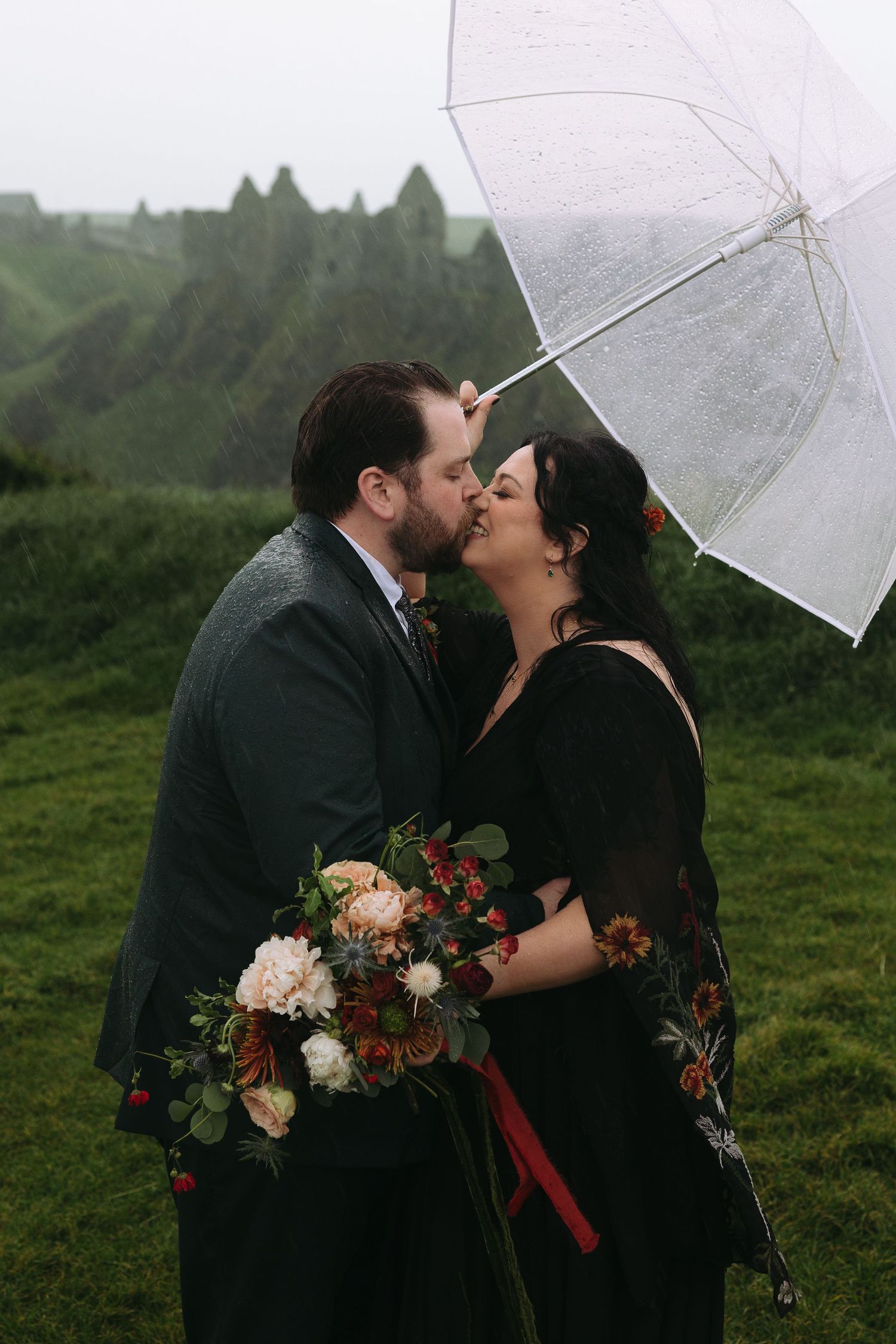 A romantic moment under a clear umbrella on a misty hillside with a beautiful autumn bouquet of flowers.