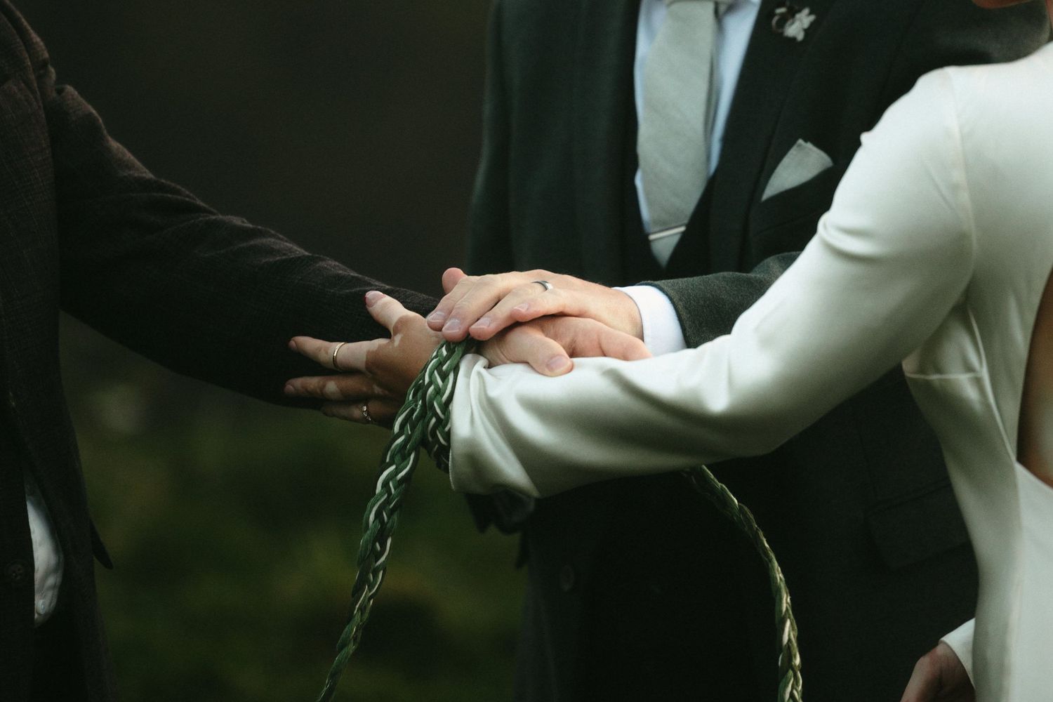 Wedding ceremony detail shots showing hands and formal attire.