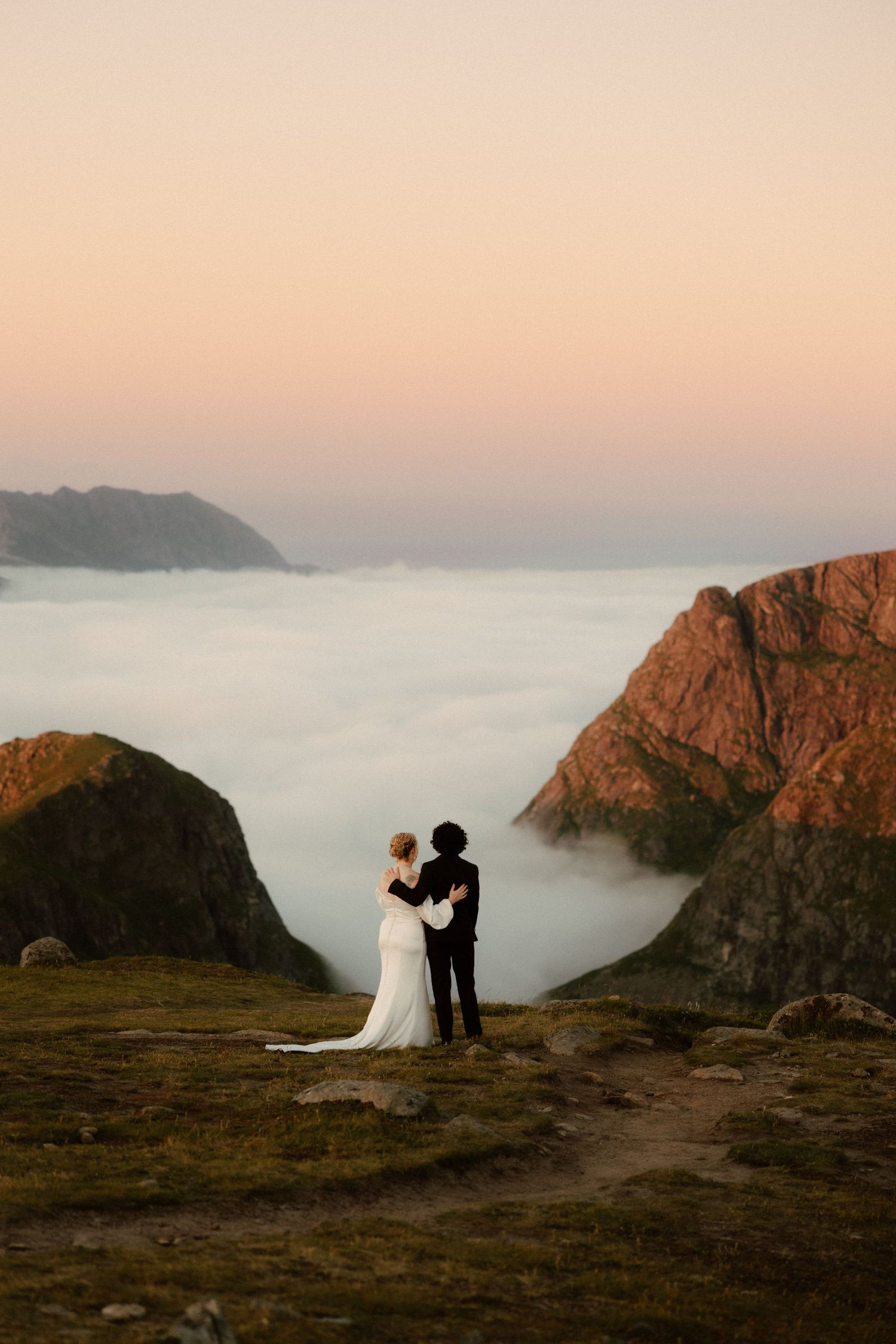 Wedding couple silhouetted against misty mountain valley during golden hour.