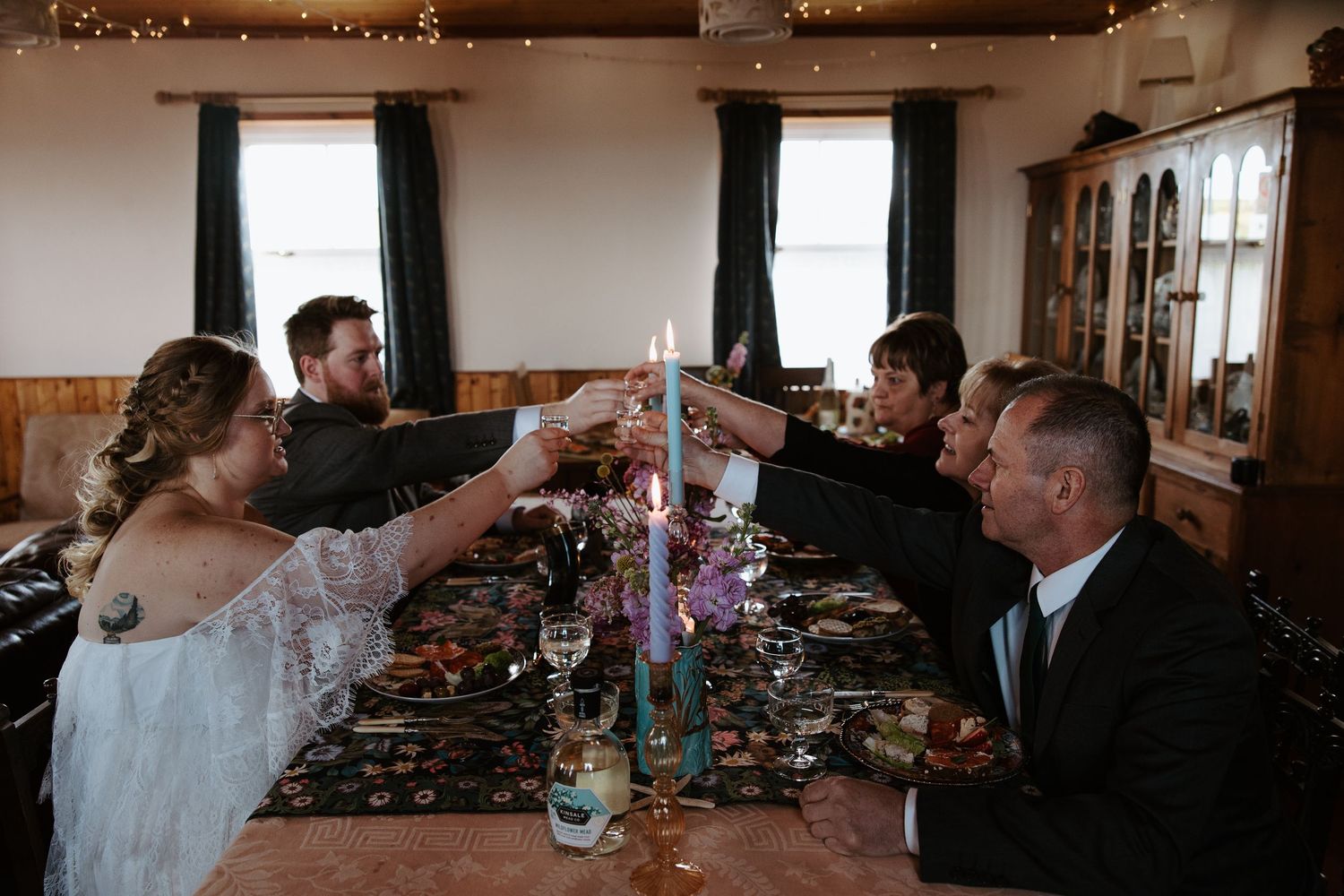 A panoramic view of a wedding reception table decorated with candles and floral centerpieces in a dimly lit venue.