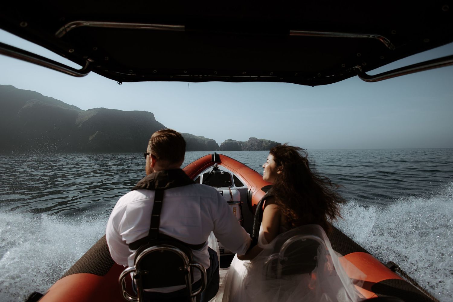Couple enjoying a scenic boat ride along the coast during sunset.
