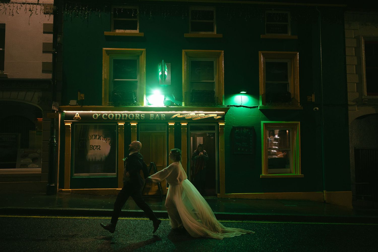 Dimly lit pub interior with green neon lighting and vintage decor.