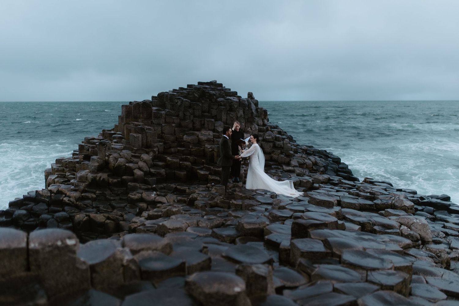 Wedding couple standing on the unique hexagonal rocks of Giant's Causeway in Northern Ireland.