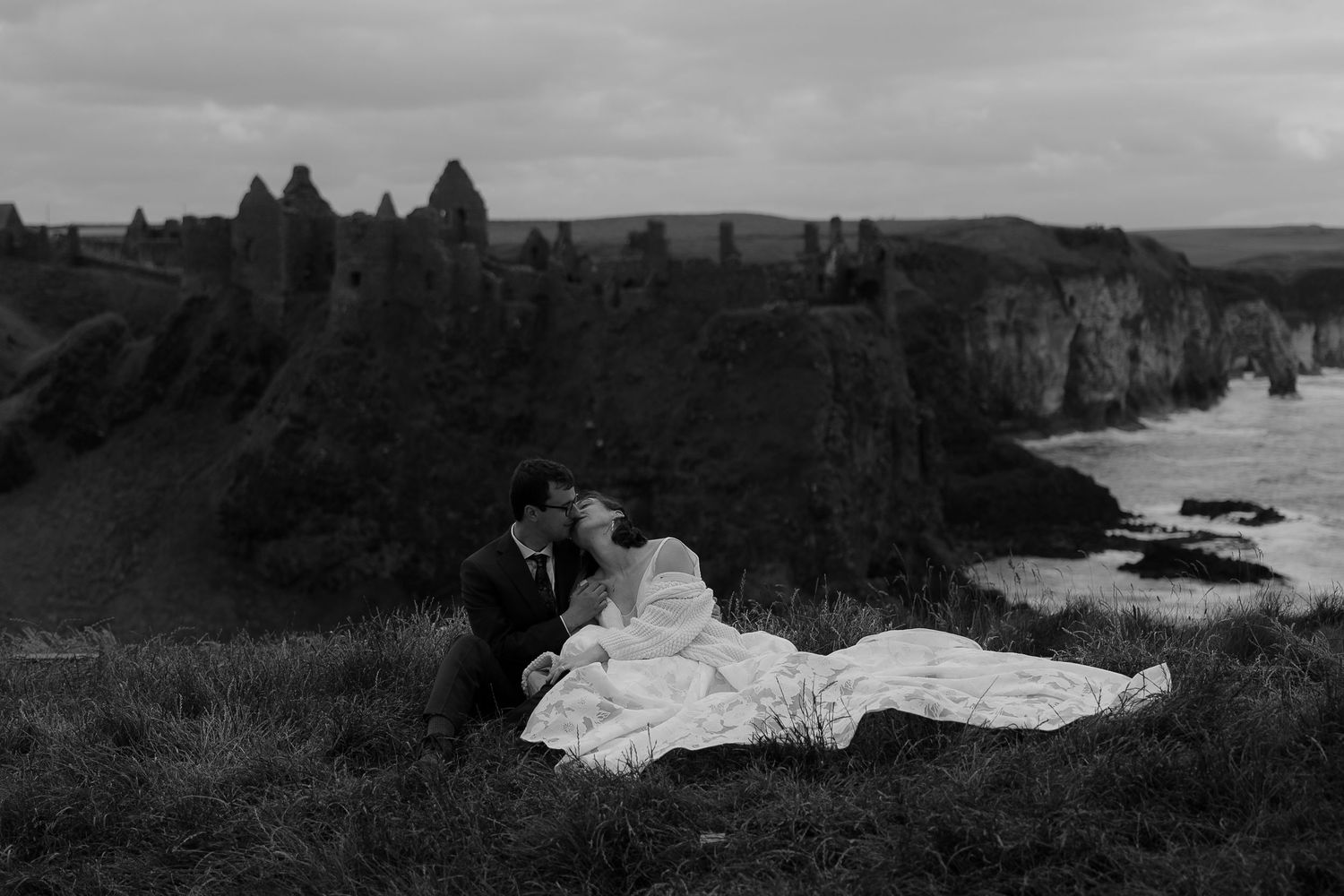 Dramatic black and white coastal landscape showing rugged cliffs and rock formations along a misty shoreline.