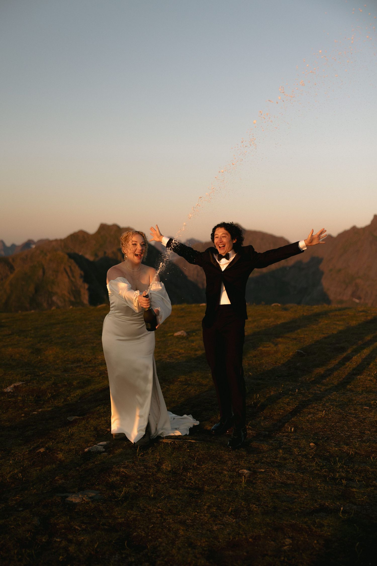 Joyful couple dances on hilltop during golden hour celebration.