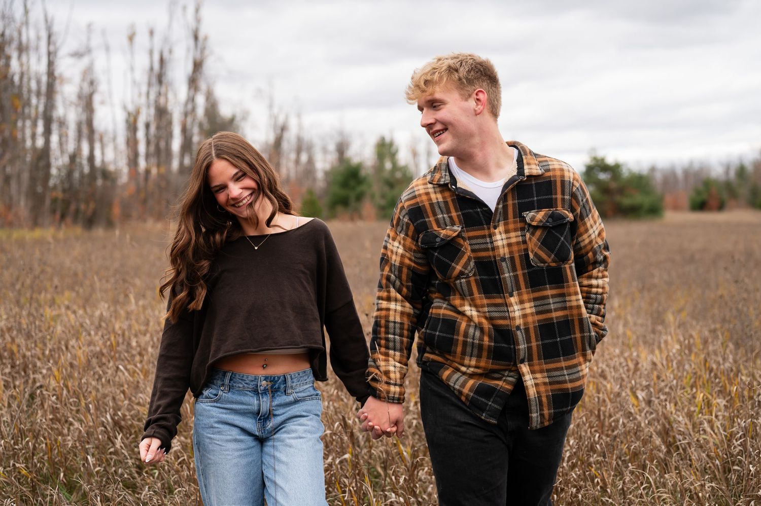 Couple sharing joyful moments in a rustic field with dried autumn grass.