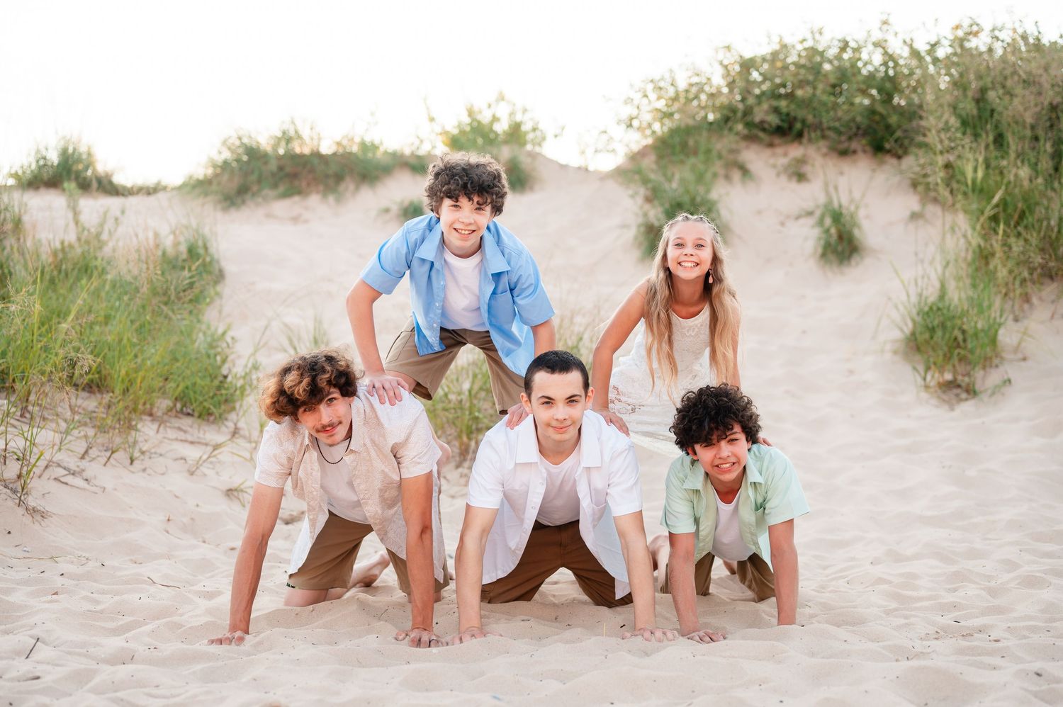 Siblings are posed in a pyramid formation during a family session at the beach.