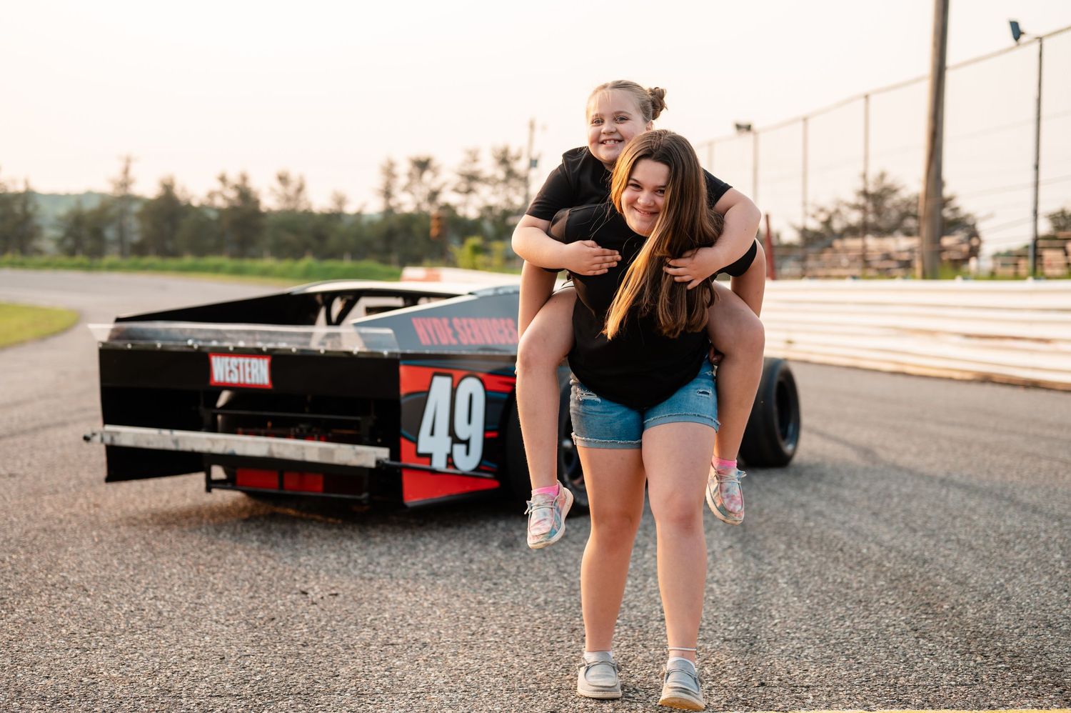 Playful moment captured near a race car numbered 49 on a track.