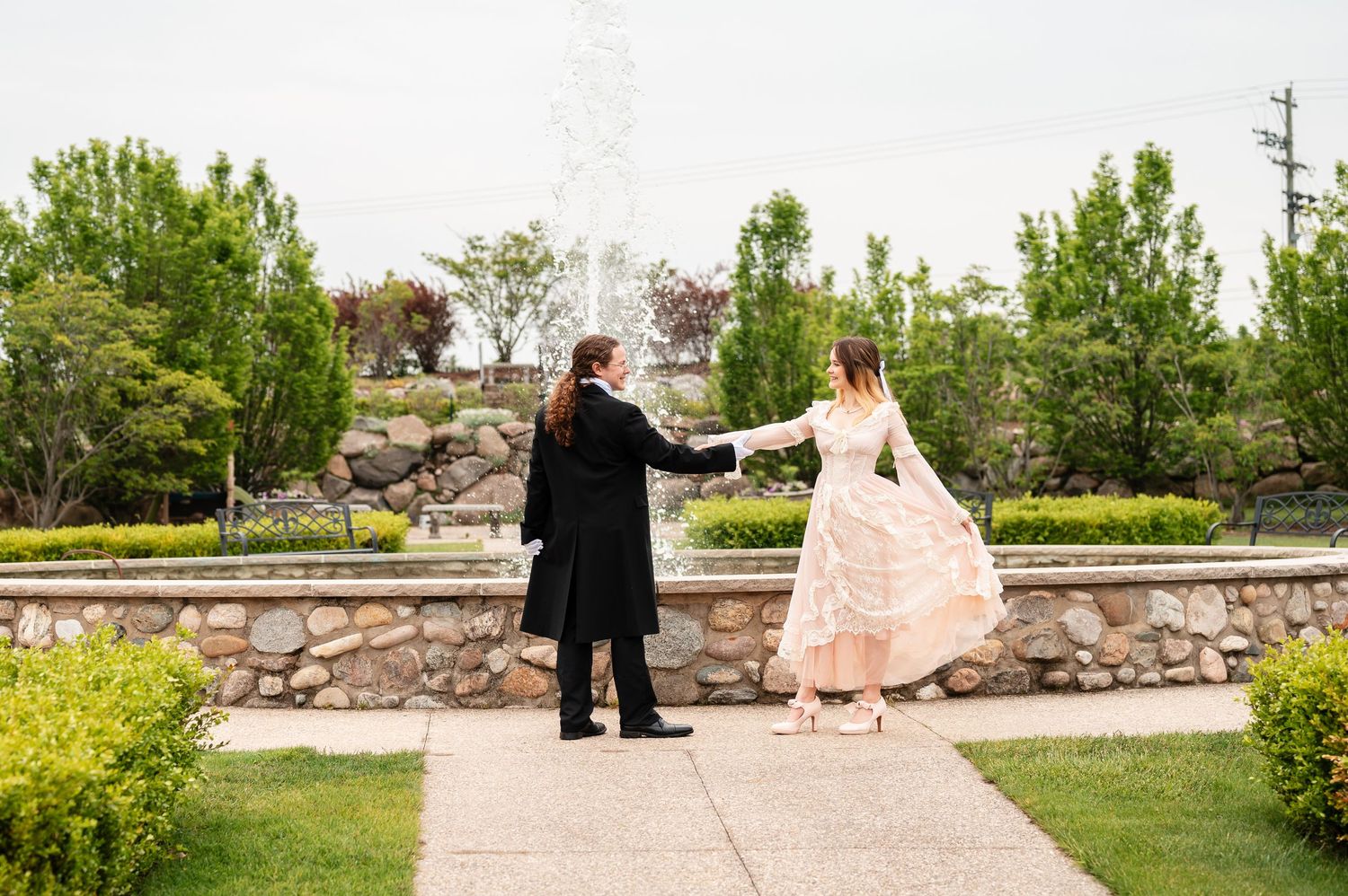 Couple walking together in a garden setting by a fountain during sunset with natural stone landscaping.