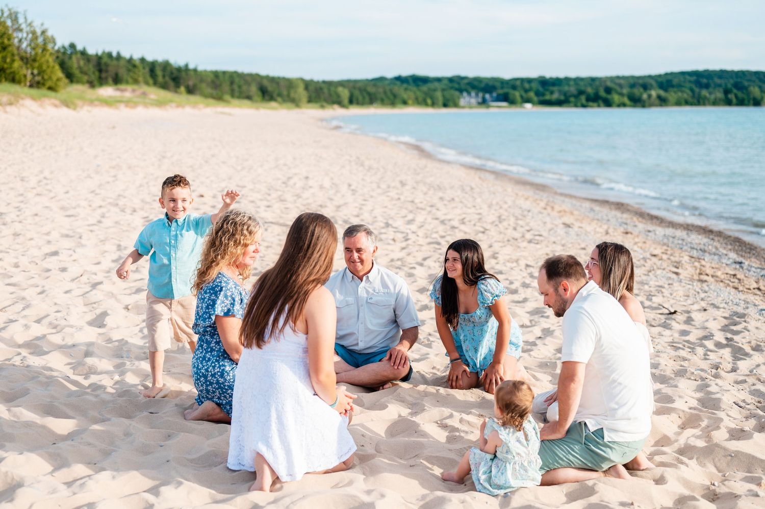 Group gathered in circle on sandy beach for casual summer photo session playing duck duck goose.
