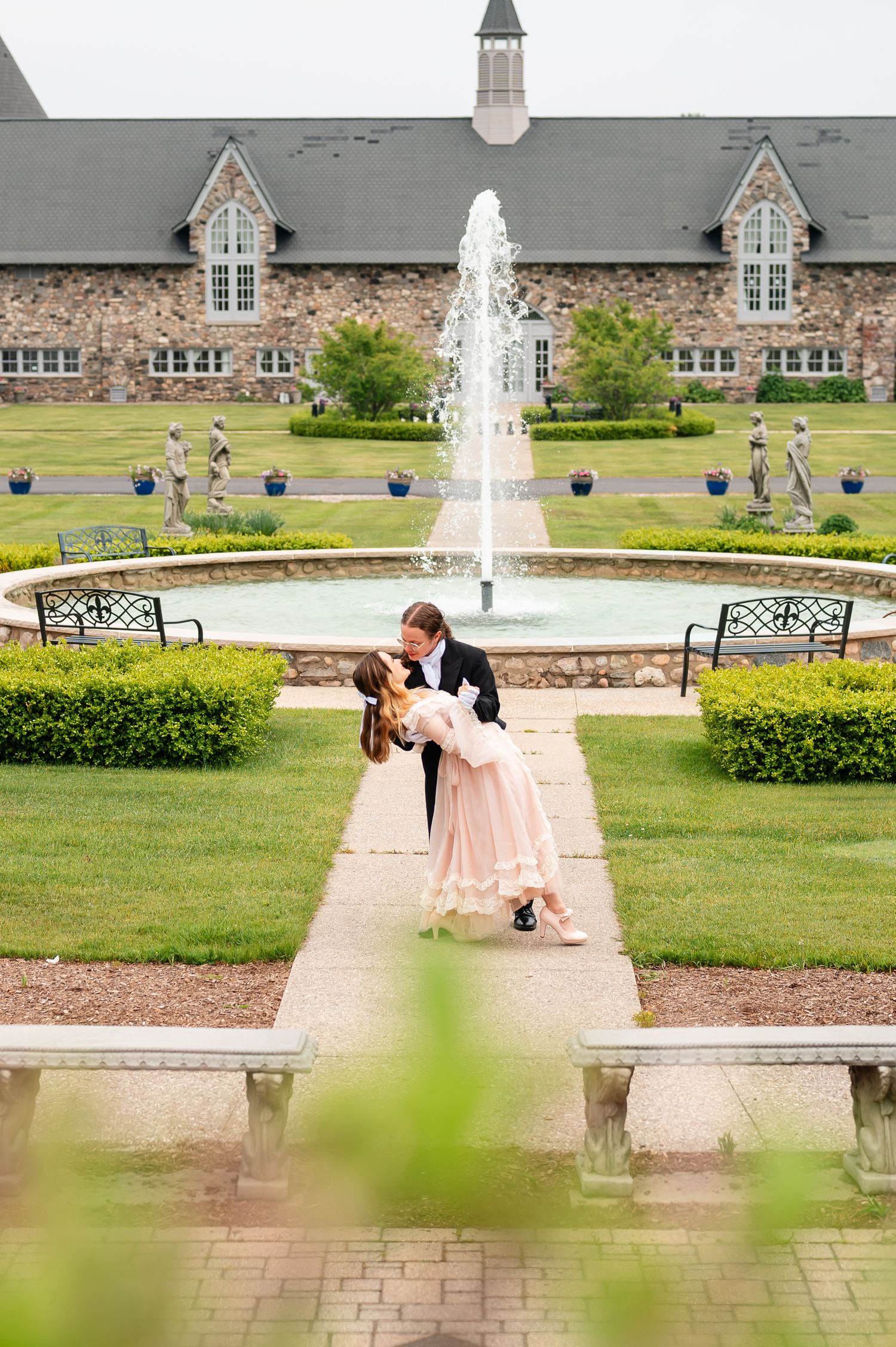 Romantic moment captured at elegant castle with fountain and manicured gardens.