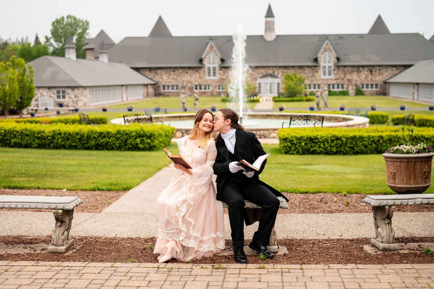 Elegant couple posing outside grand estate building with manicured gardens.