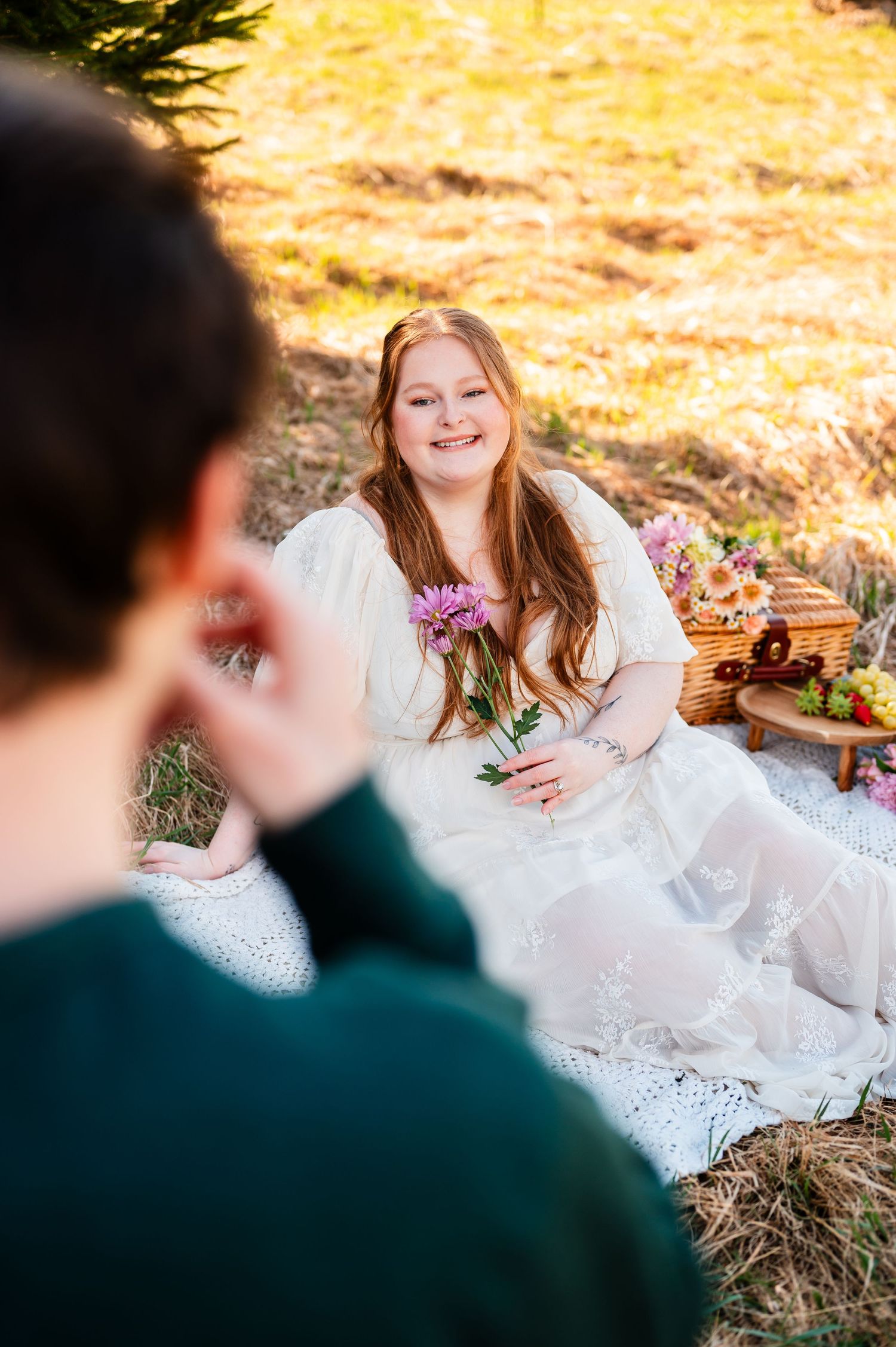 A picnic scene outdoors with a white dress and flowers in golden sunlight.
