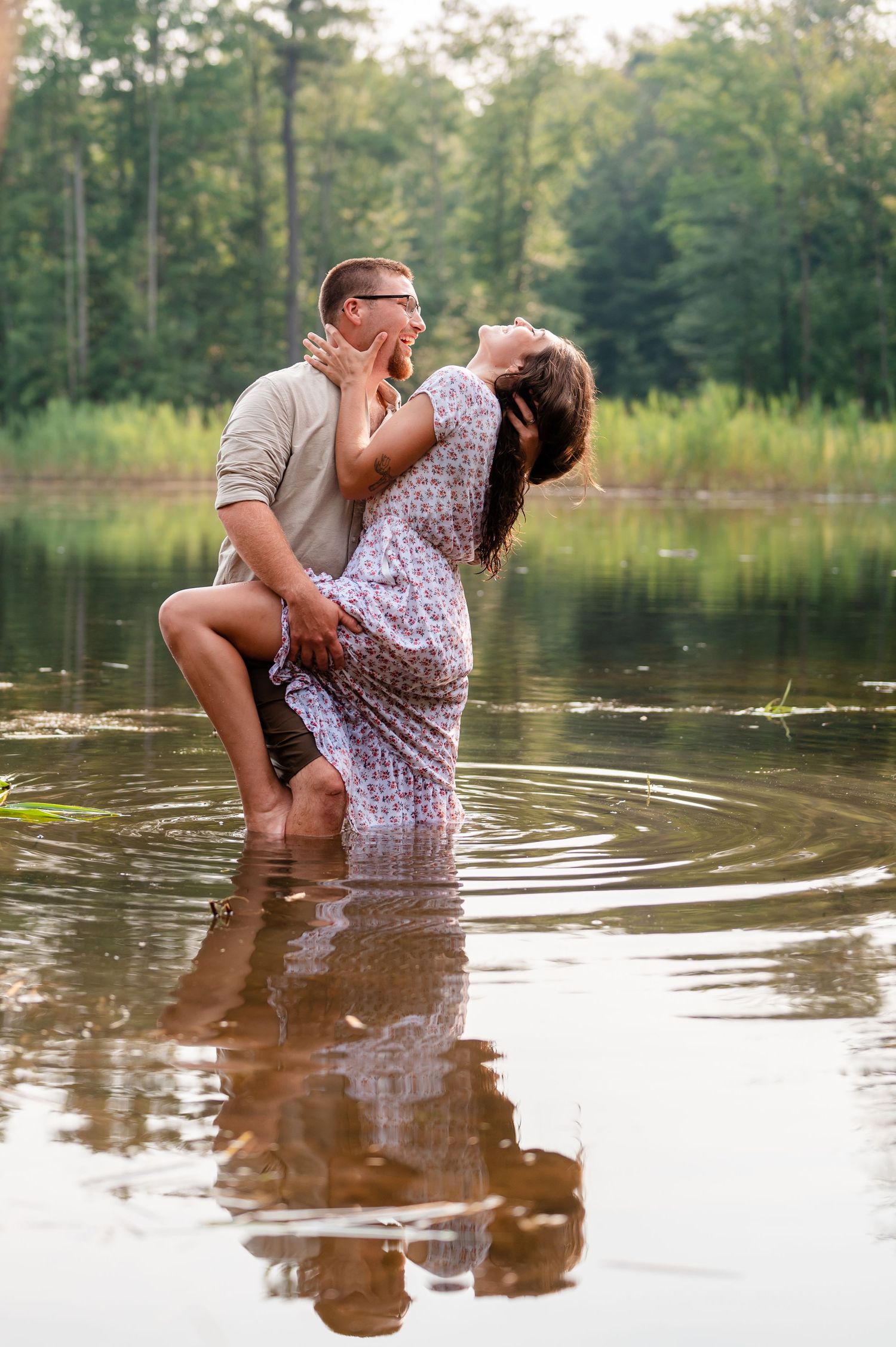 Couple sharing romantic moments while wading in peaceful lake waters at sunset.