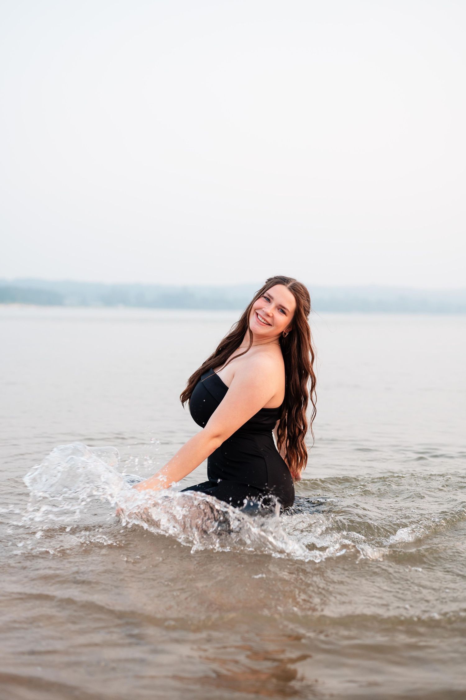 A girl with long hair splashes and plays in lake water in Northern Michigan