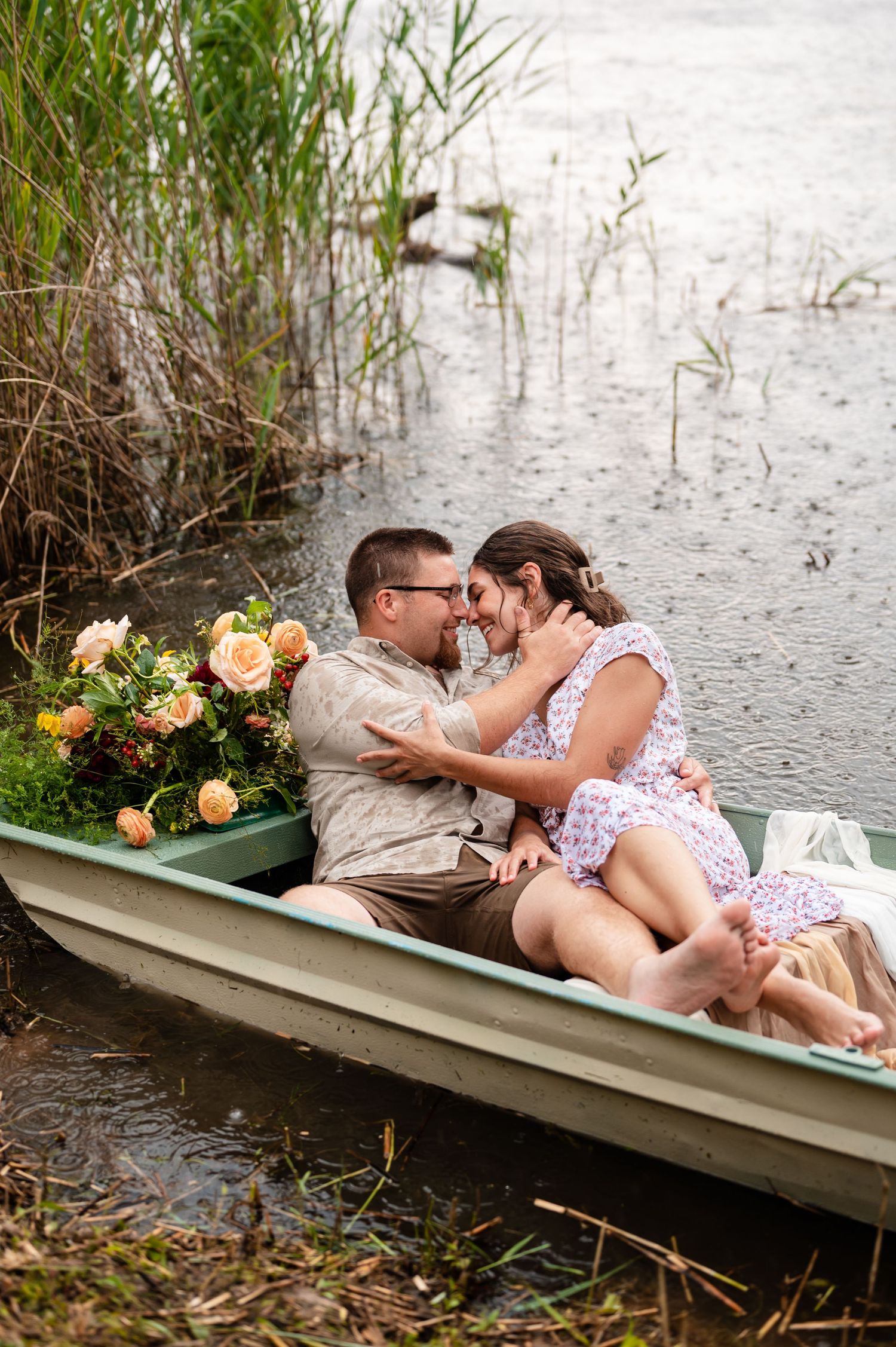 Intimate moment between couple in small boat surrounded by water and weeds.