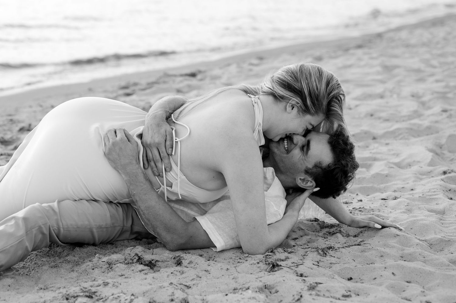 Black and white artistic photos of a figure lying on a sandy beach.