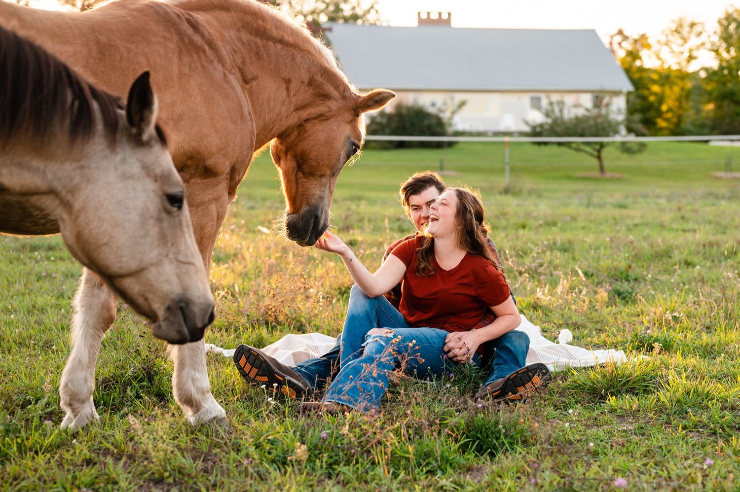 Couple relaxing on grass with friendly horse in pastoral setting.