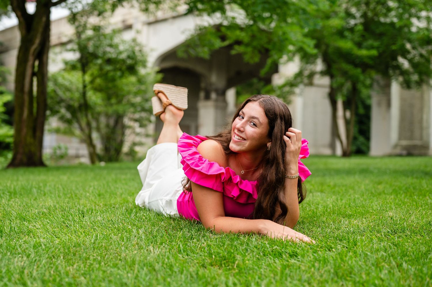 Outdoor portrait on grass wearing vibrant pink ruffled top.