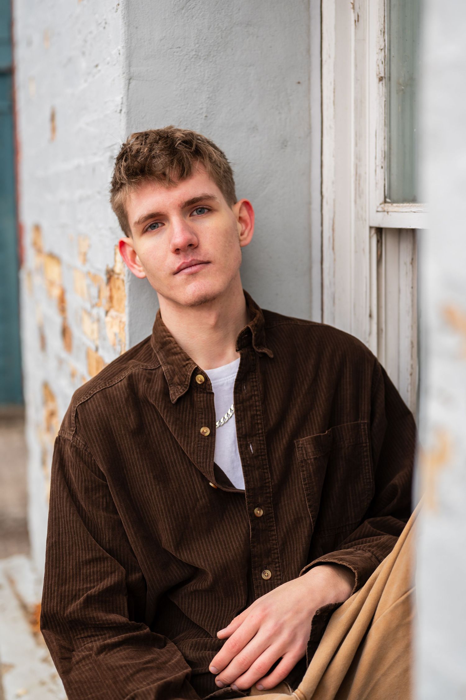 Portrait against white wall wearing brown corduroy jacket.