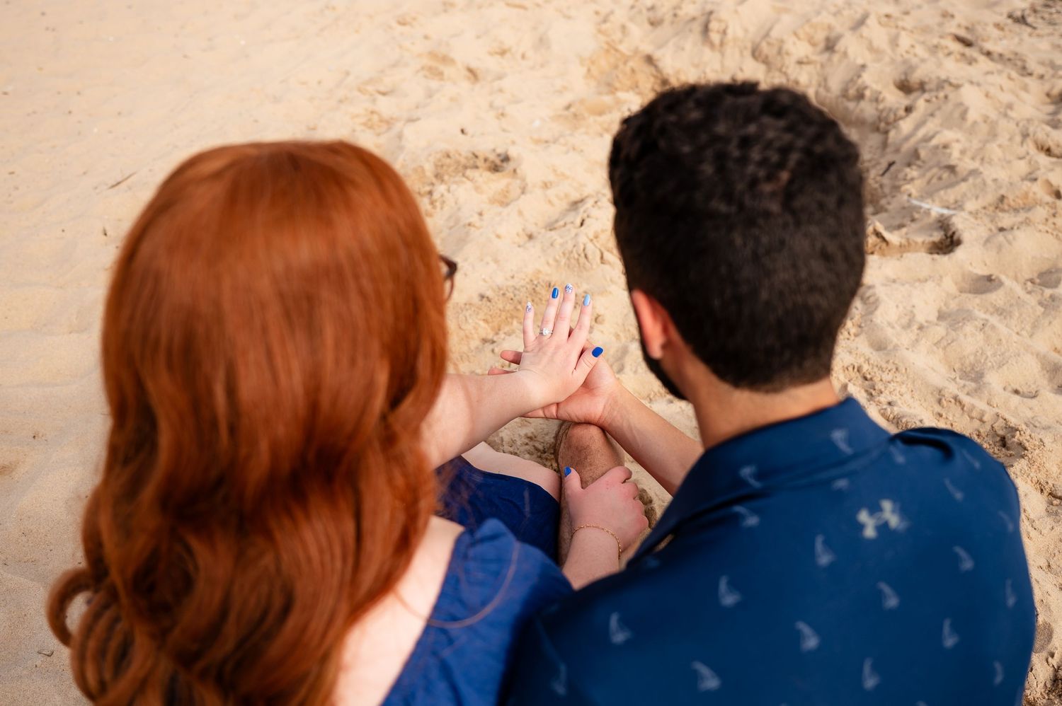 A close-up shot of hands touching against the sand during an engagement session in Petoskey Northern Michigan.