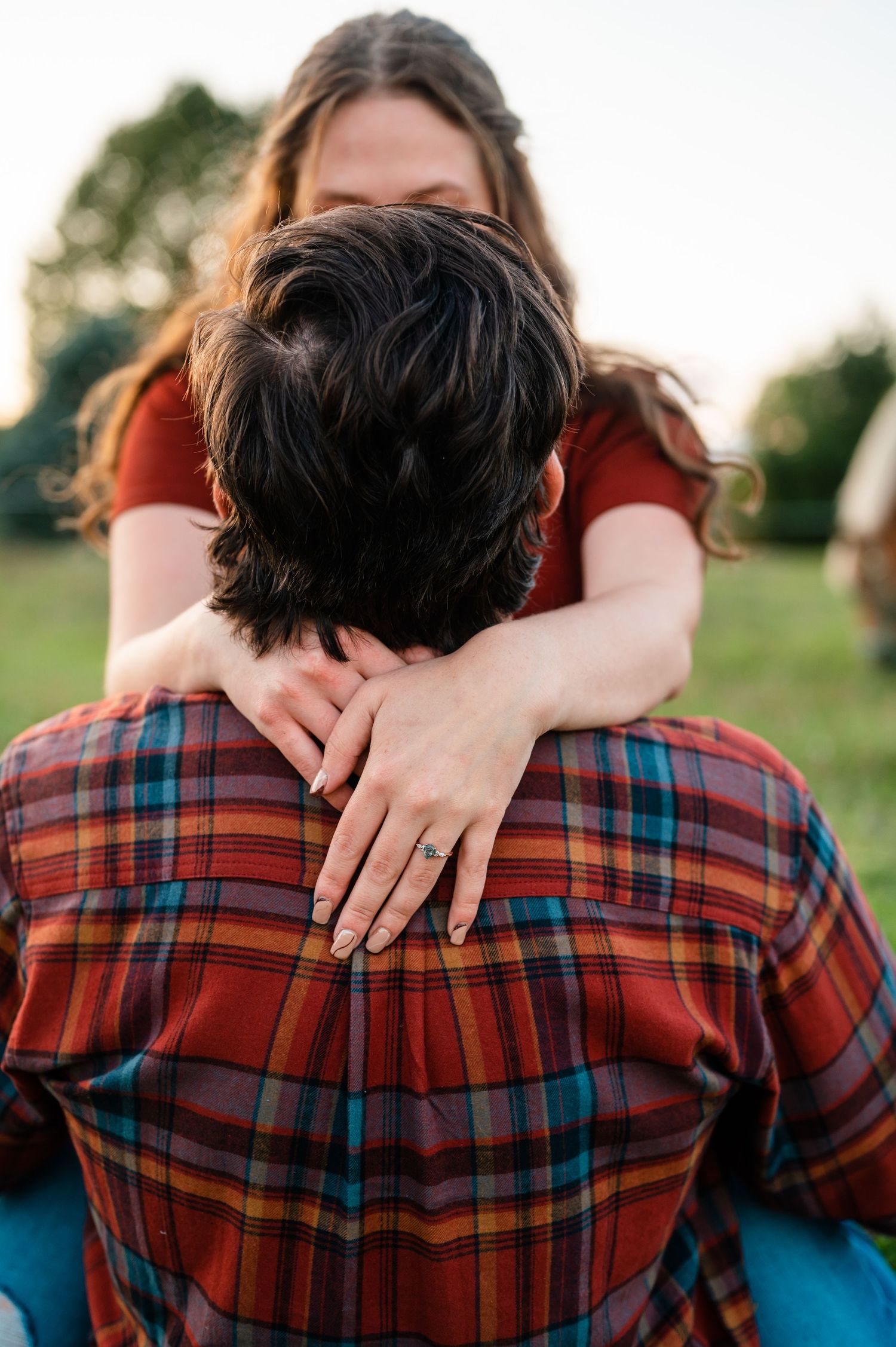Close-up of embrace showing plaid shirt and ring detail.