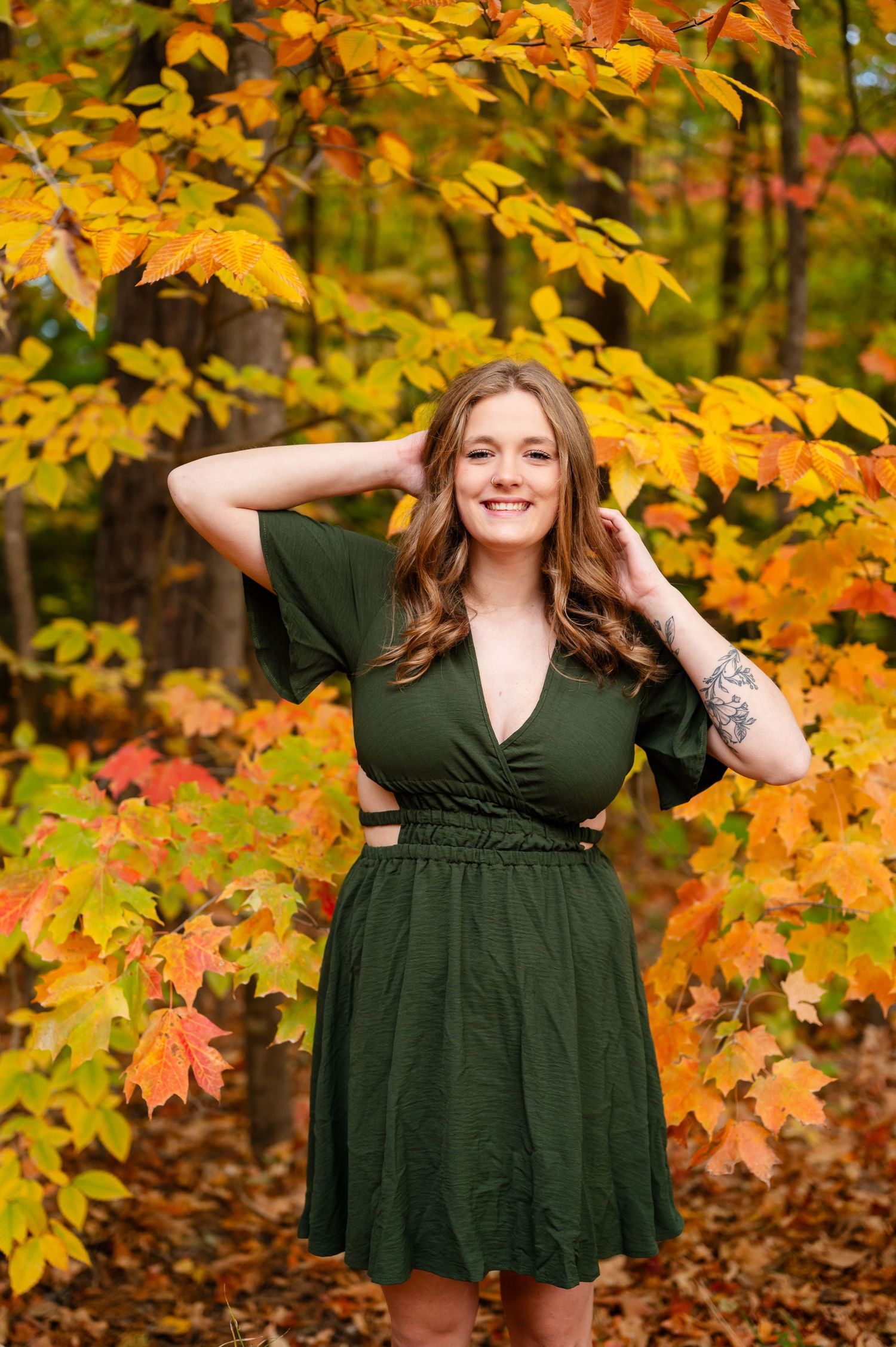Fall portrait session with vibrant yellow maple leaves and forest backdrop.