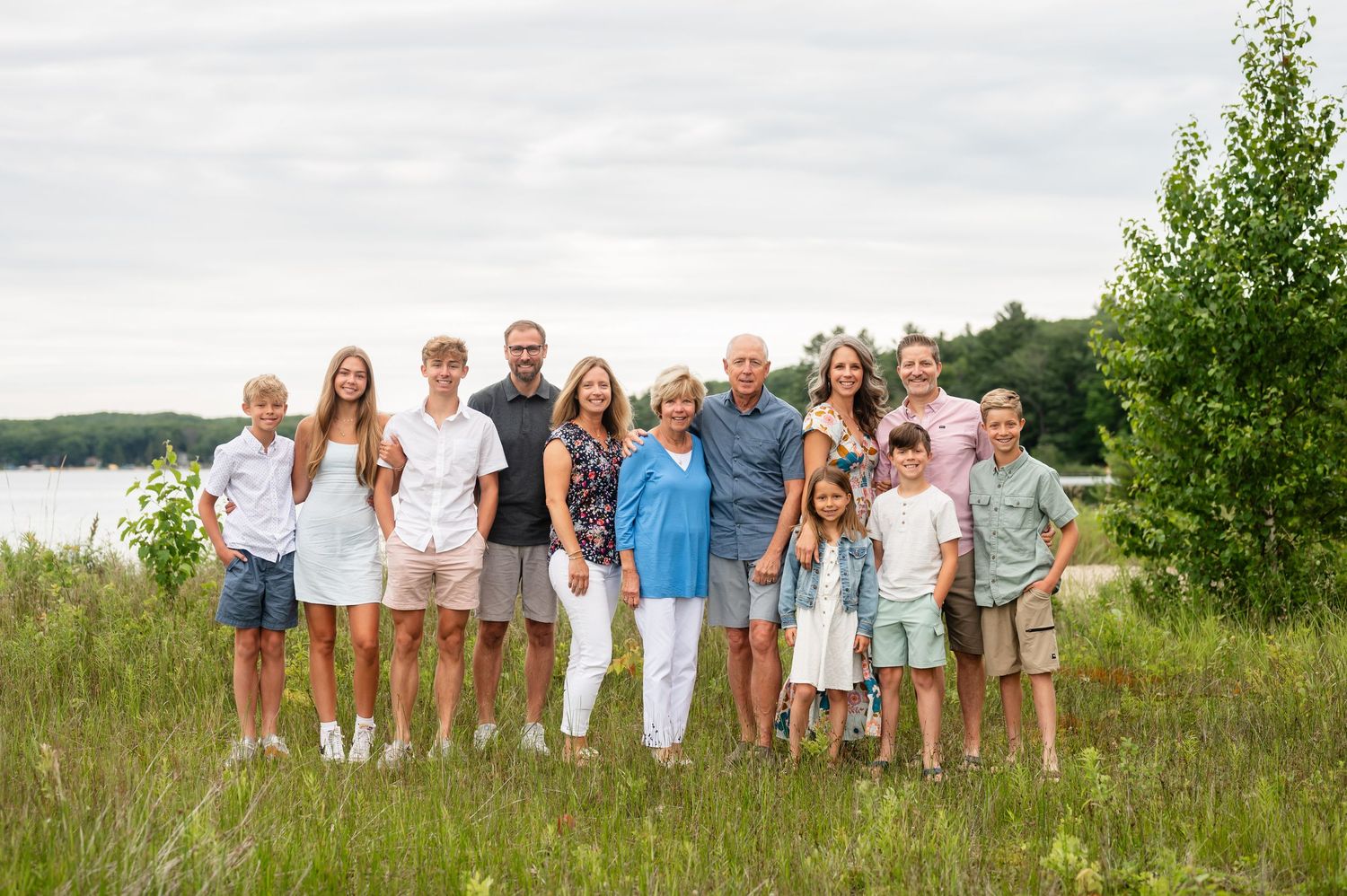 Extended family gathered at a lake wearing coordinated white and blue outfits.