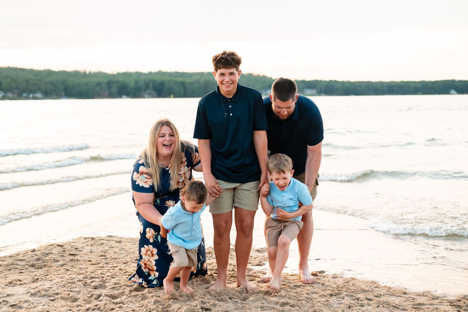 A family session enjoying playful moment together at water's edge during beach sunset in Gaylord Michigan.