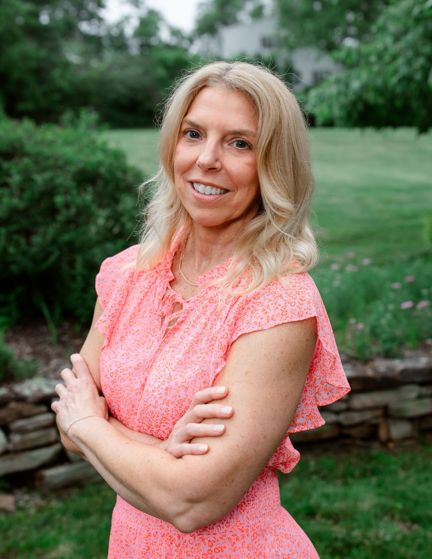 Person in coral dress posing outdoors in garden setting.