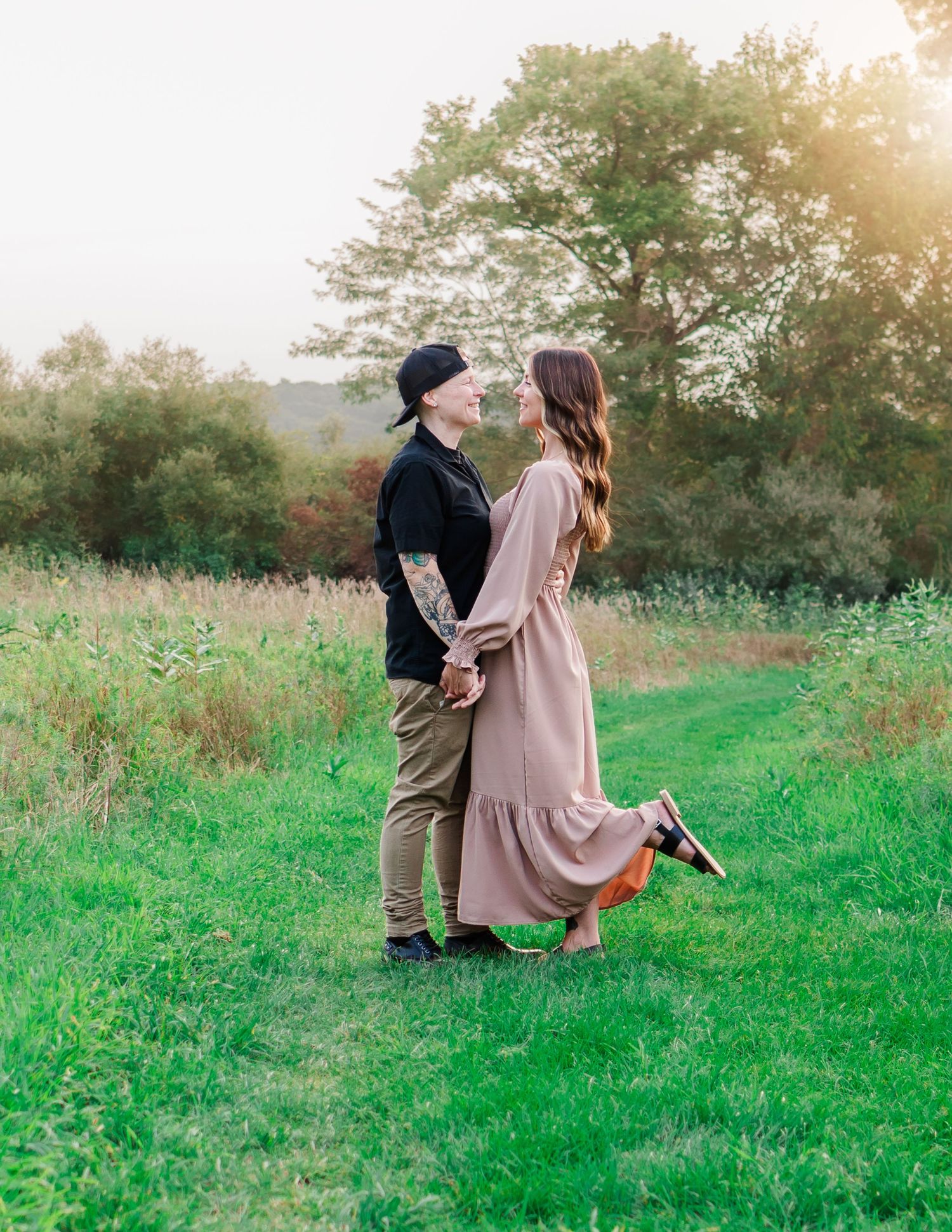 Romantic sunset photoshoot in a green meadow with soft golden lighting.