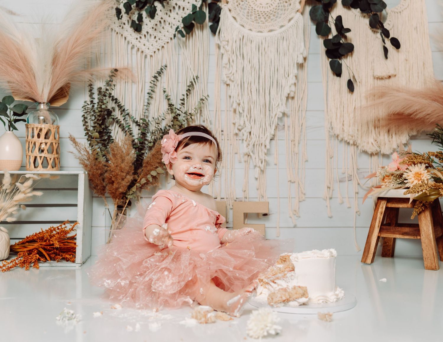 First birthday photoshoot featuring pink tulle dress and rustic decorative elements.